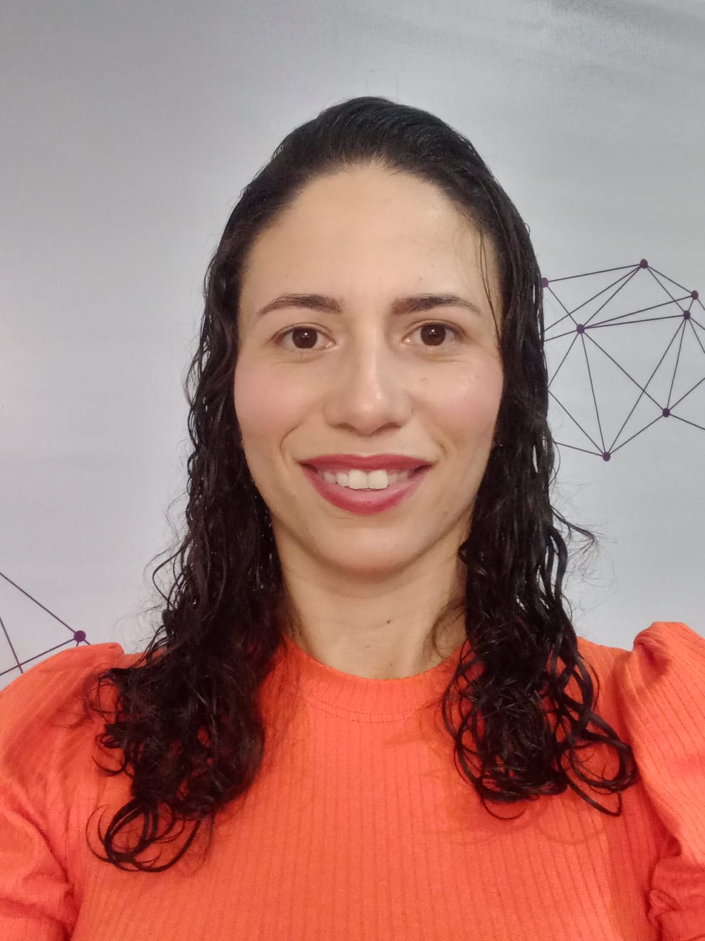 Ana Gabriella de Oliveira Sardinha smiling in front of a wall with geometric designs.